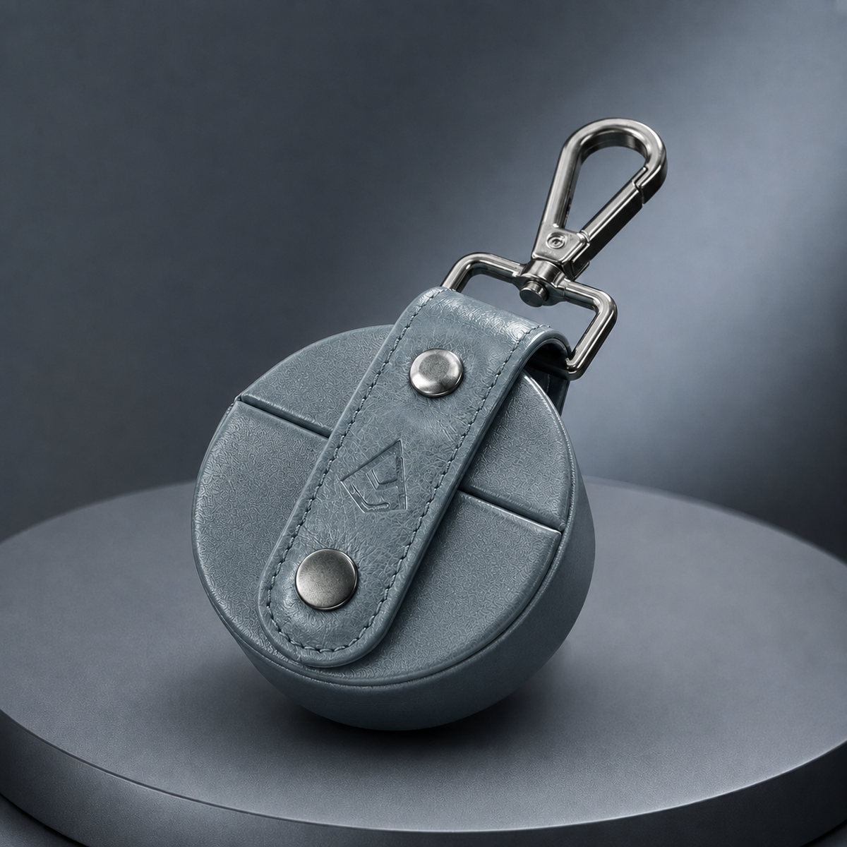 Navy leather AirSpin case at an angle, showing the stitched round body and clip